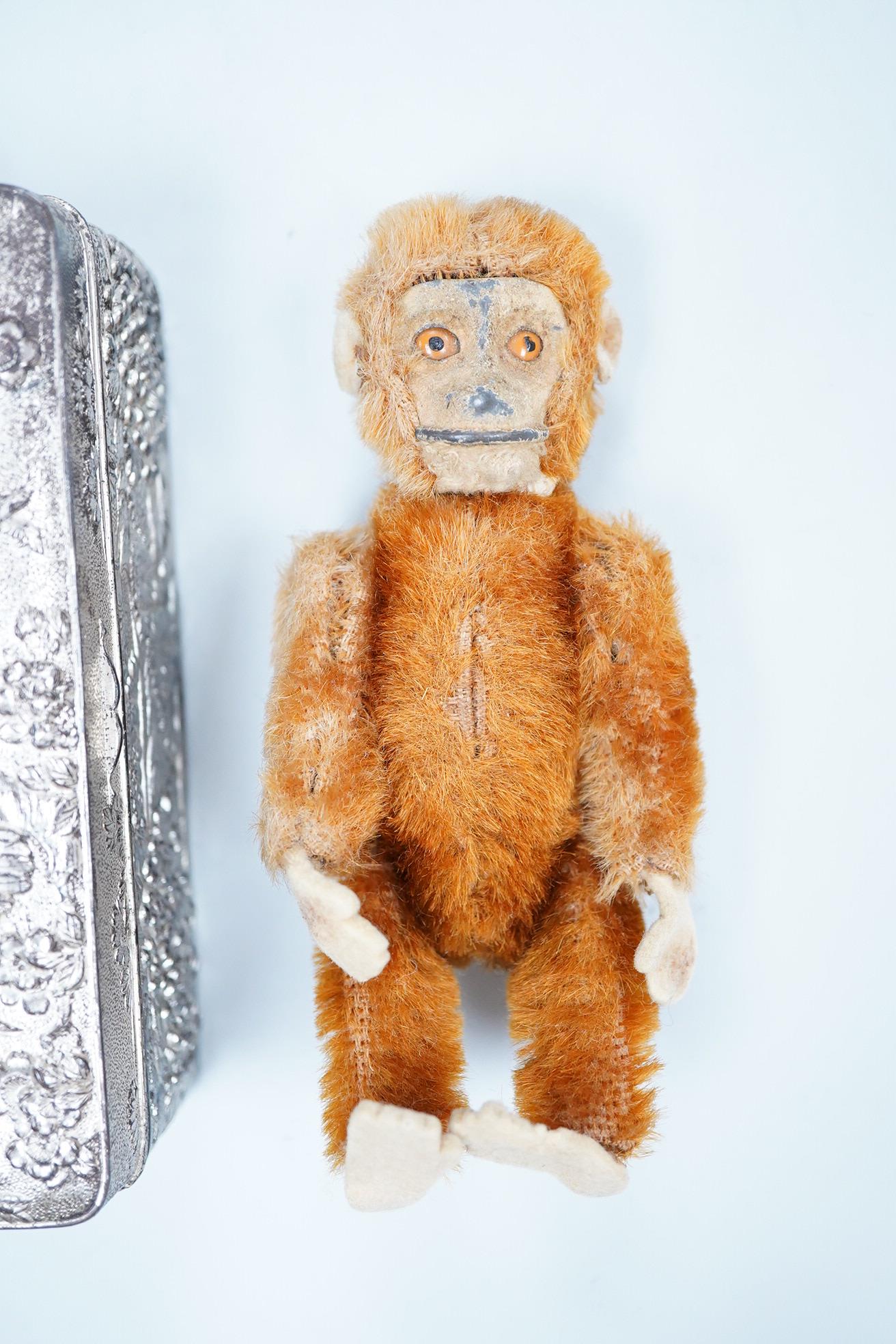 A German Schuco scent bottle monkey, with mohair body containing a glass bottle, together with a white metal Japanese style lid box decorated with a floral landscape and bird of prey to the lid